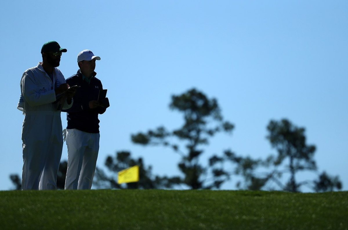 Jordan Spieth and caddie Michael Greller prepare to play his shot from the fourth tee during the first round of the 2016 Masters Tournament at Augusta National Golf Club.