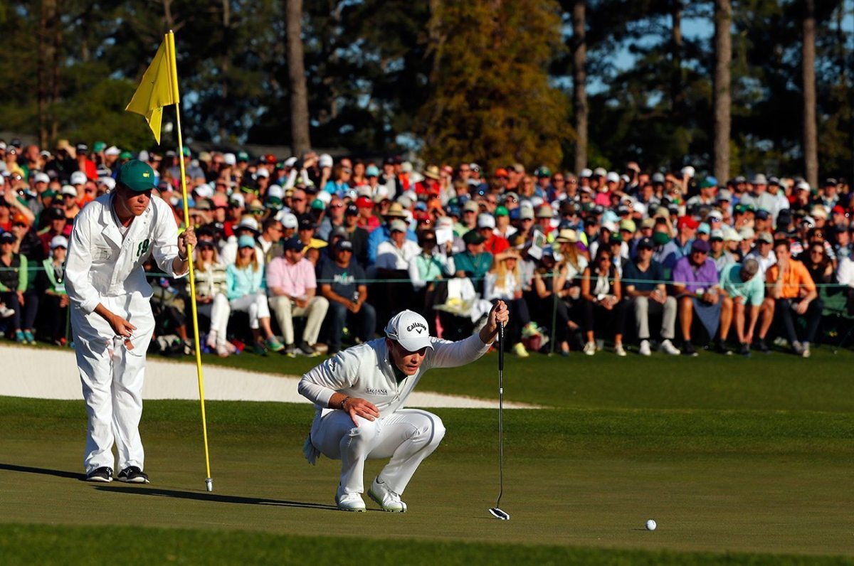 Danny Willett and caddie Jonathan Smart line up a putt on the 18th green during the final round of the 2016 Masters Tournament at Augusta National Golf Club.